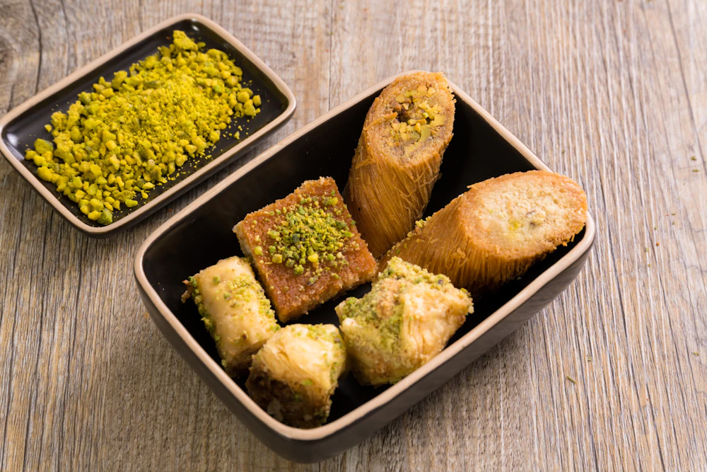 Tray of golden baklava pieces topped with crushed pistachios